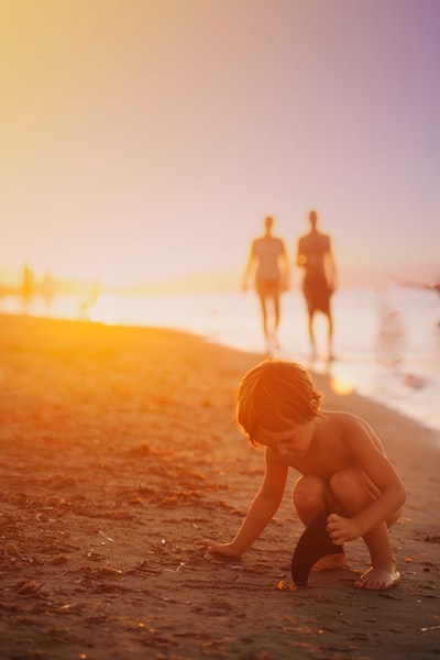 日落时在海边玩沙子的男孩